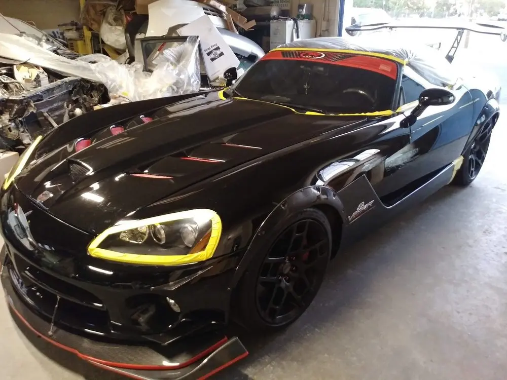 Black Dodge Viper with headlights masked in yellow tape after paint work
