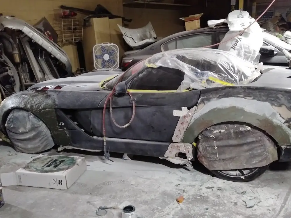 Dark sports car in primer with fender body work under way in the shop