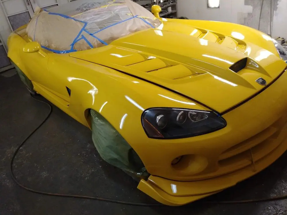 Yellow Dodge Viper masked with paper and tape for paint in the spray booth